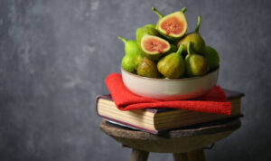 Ripe figs heap on book and old wooden stool in studio